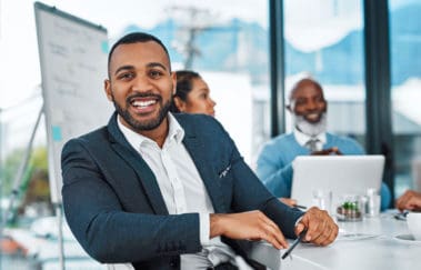 Head of real estate brokerage firm smiling as he meets with his team of brokers