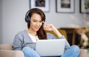 woman sitting on couch listens to real estate audio courses