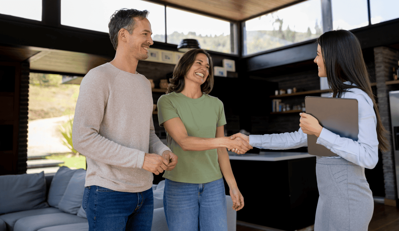 real estate agent shakes hands with couple